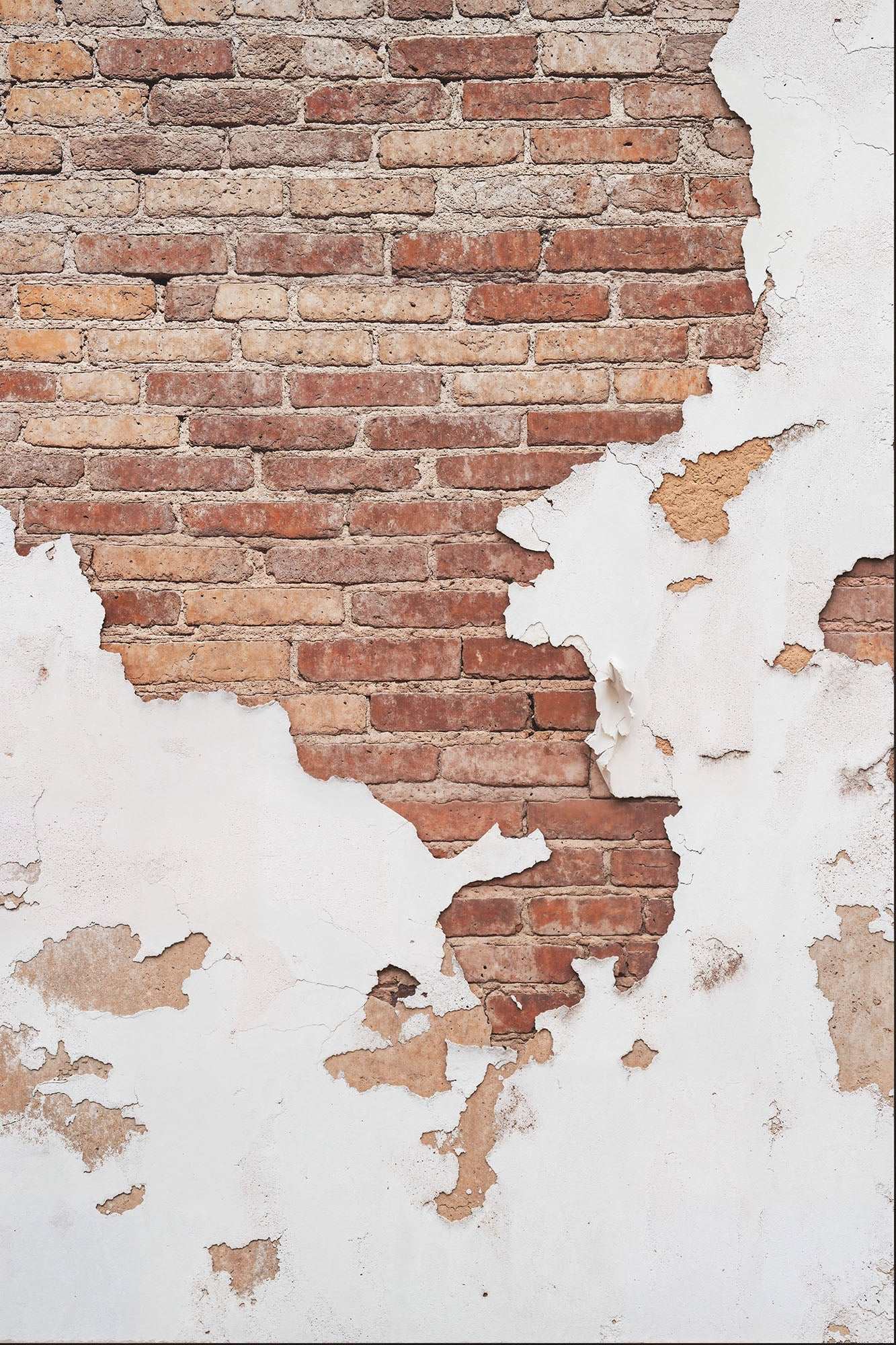 Worn masonry with peeling white paint revealing red brick wall beneath.