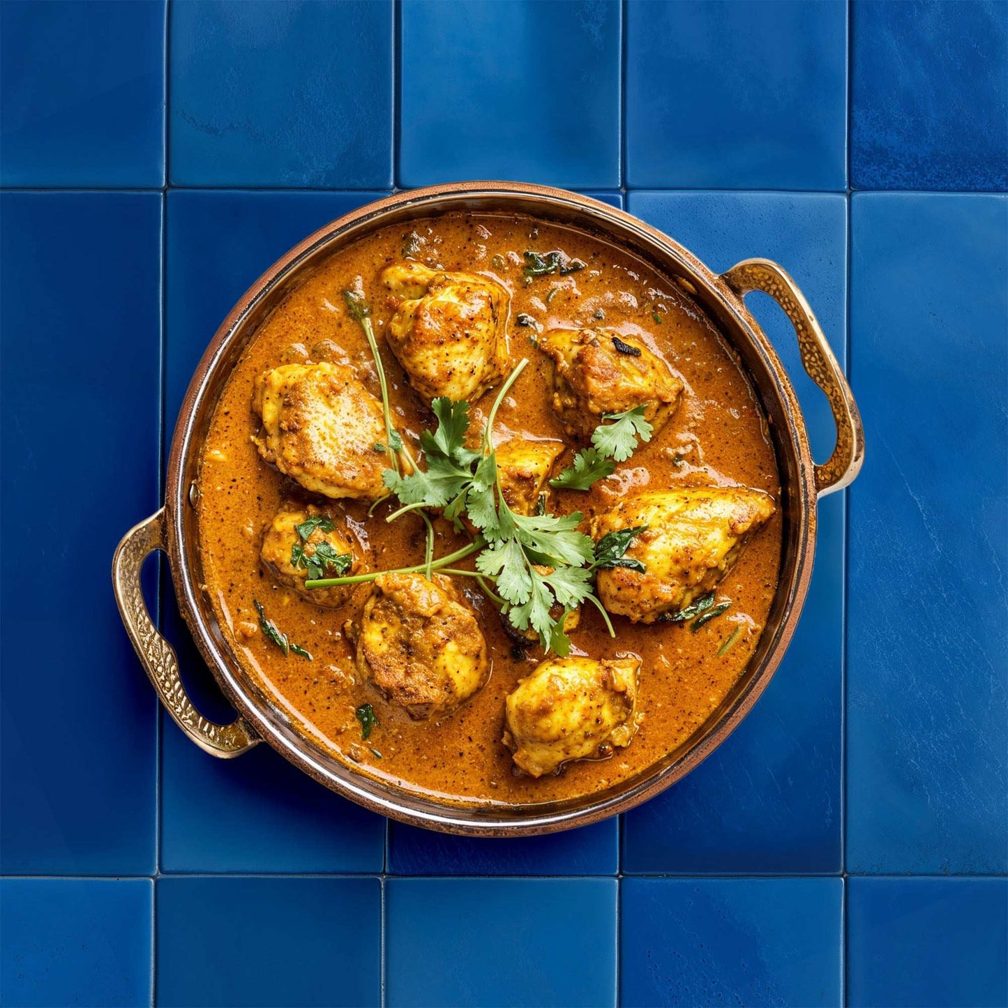Deep blue tile backdrop with a dish in a round copper pan.