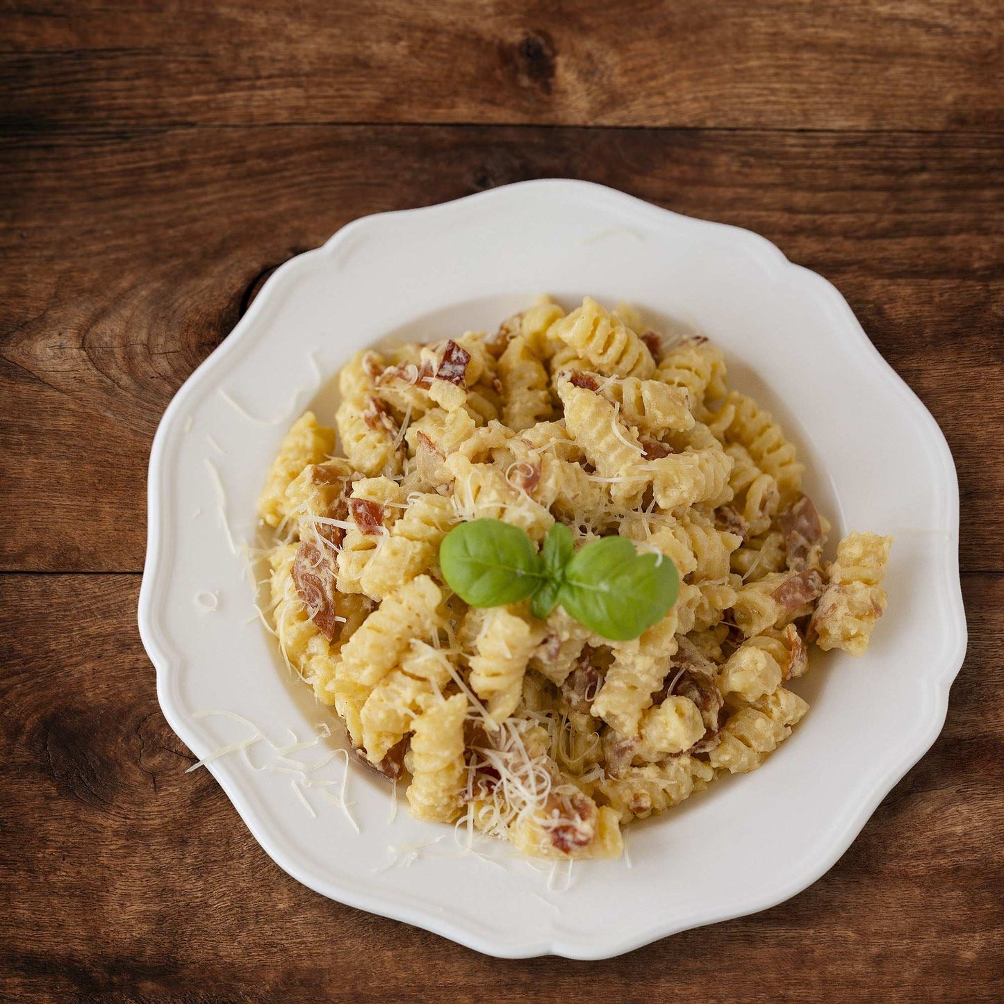 Rustic walnut wood backdrop with pasta on white plate.