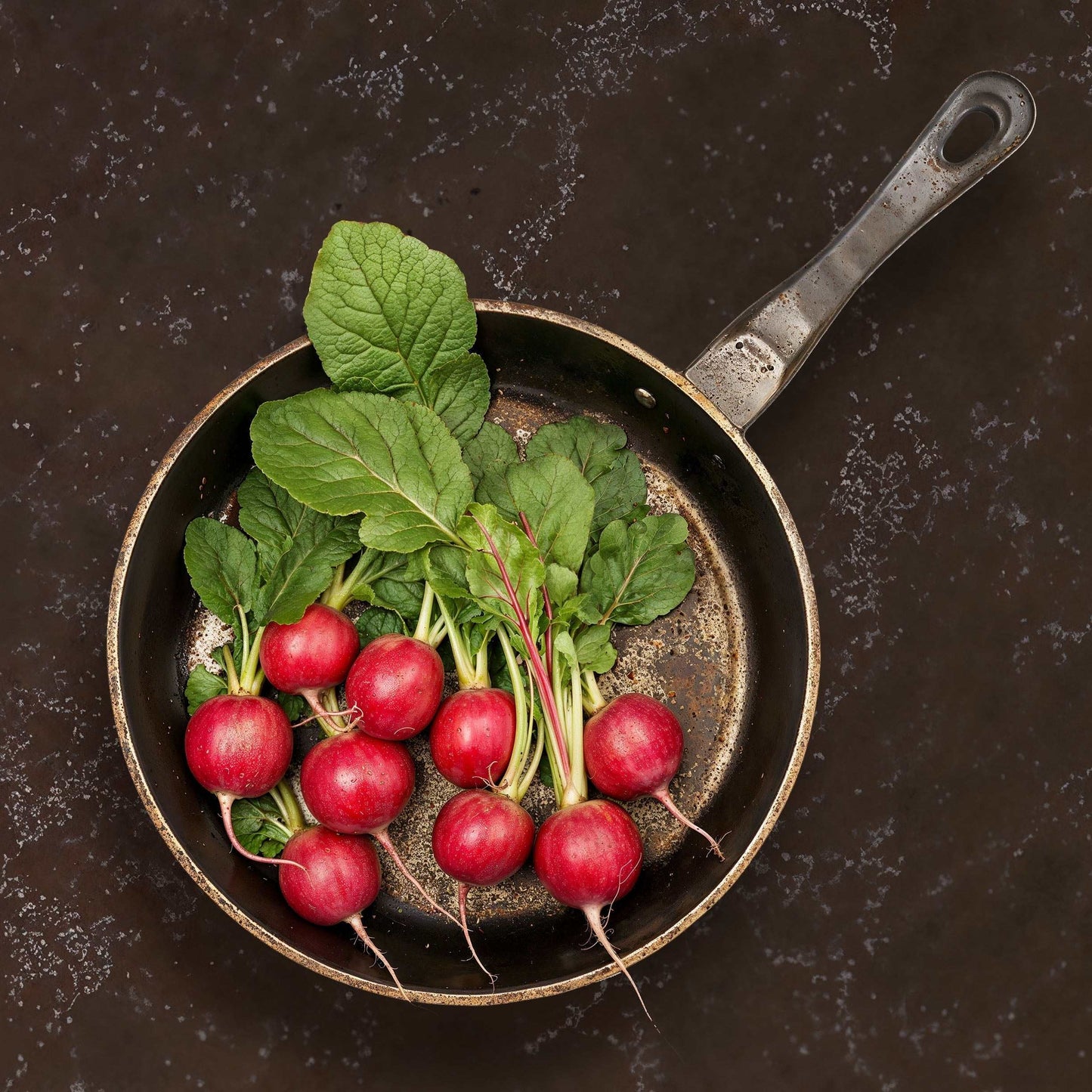 Dark brown matte 'Amalfi Palace' stone texture with radishes in a rustic pan.