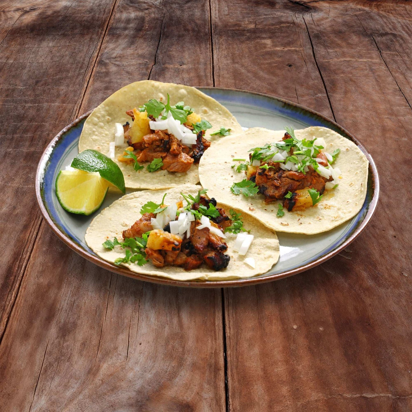 Rustic tacos on a weathered timber backdrop with lime garnish.